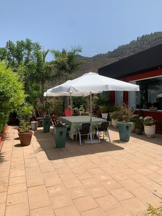 Un patio con una mesa y sillas bajo una sombrilla.