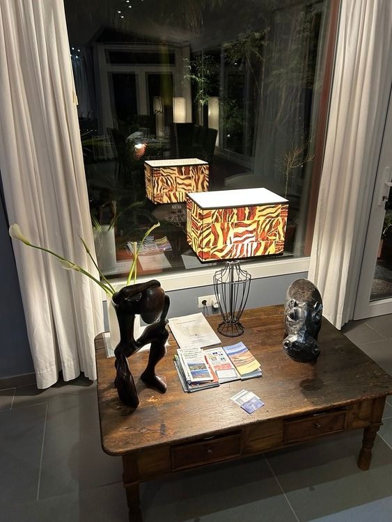 Una mesa de madera con una estatua encima frente a una ventana.
