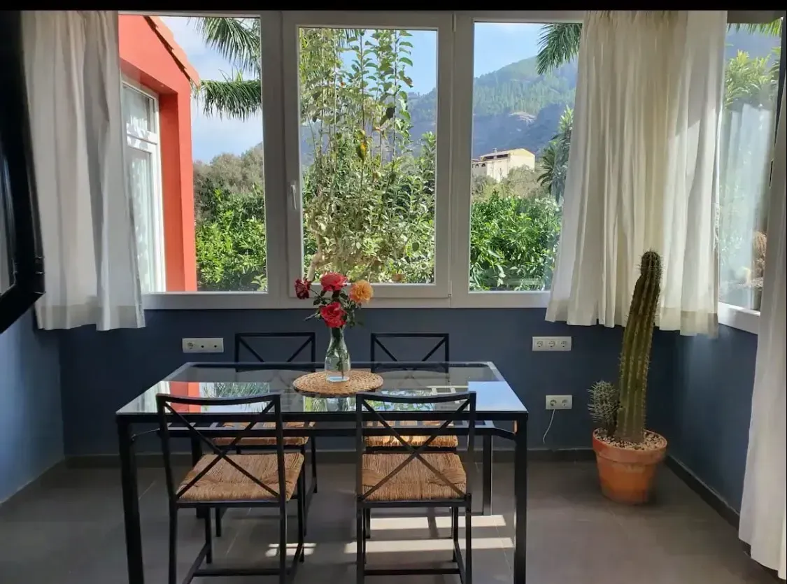Un comedor con una mesa y sillas frente a una ventana.