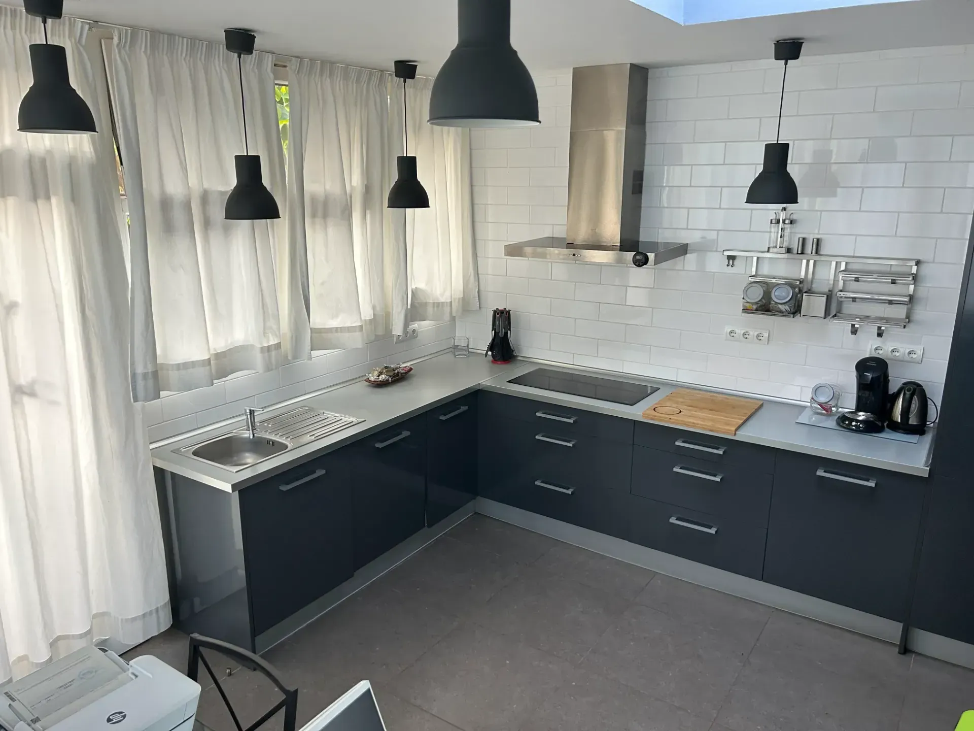 Una cocina con gabinetes negros y encimeras blancas.