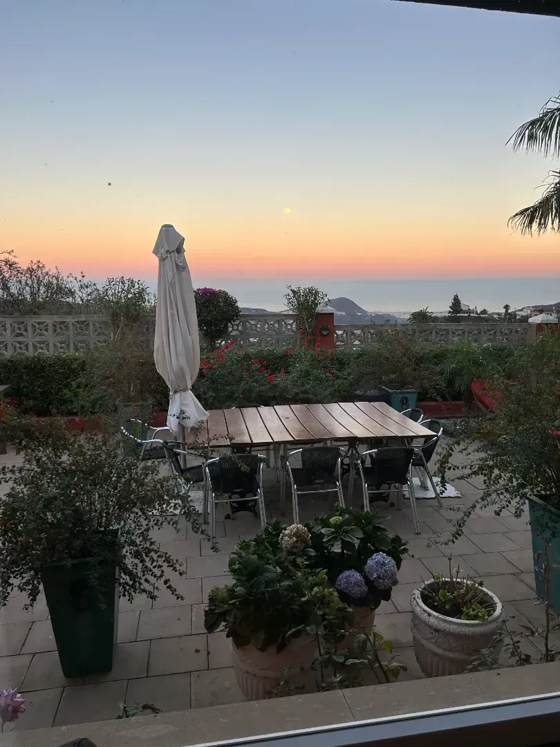 Una vista de un patio con una mesa y sillas al atardecer.