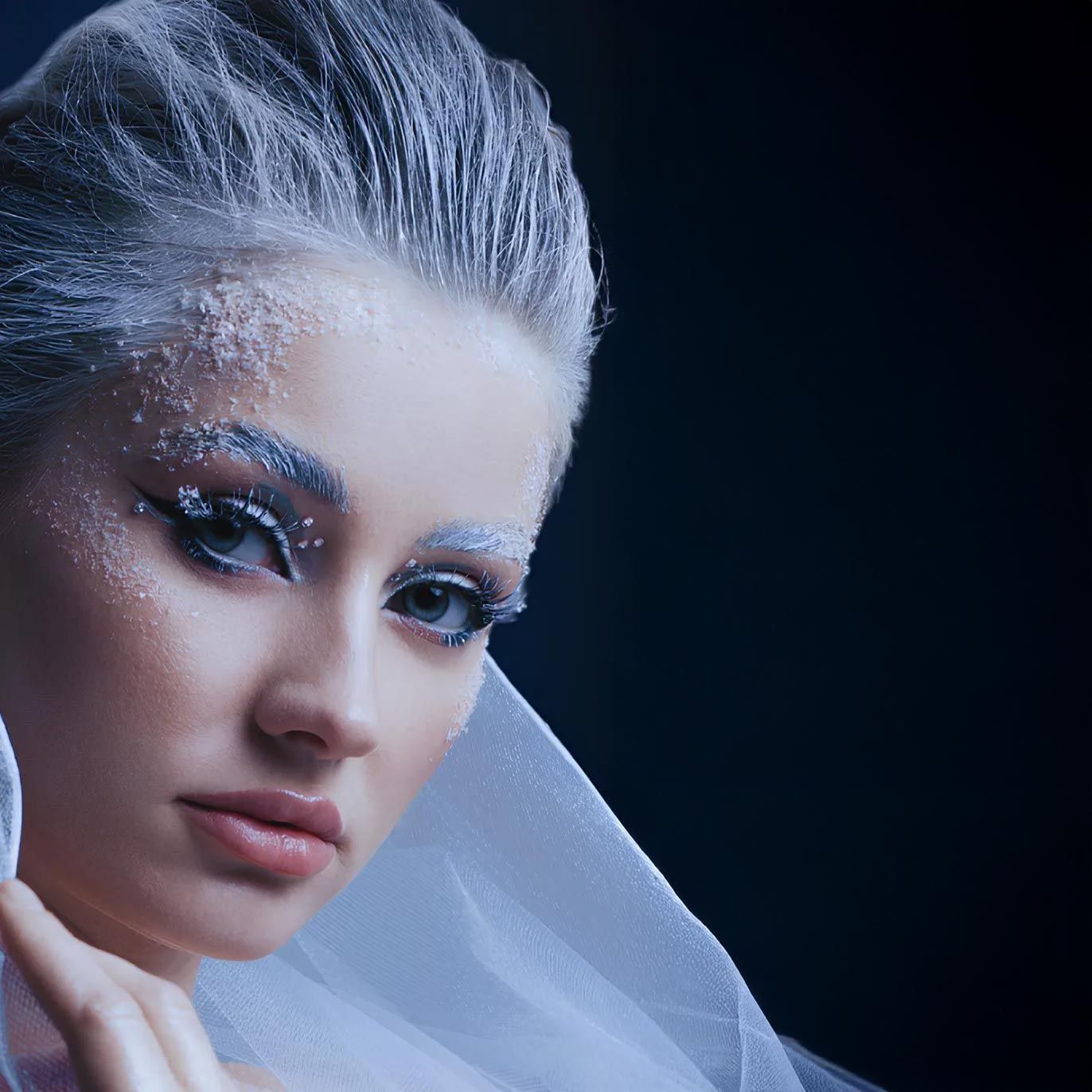Portrait en gros plan d'une femme aux cheveux argentés et au maquillage pailleté sur fond sombre