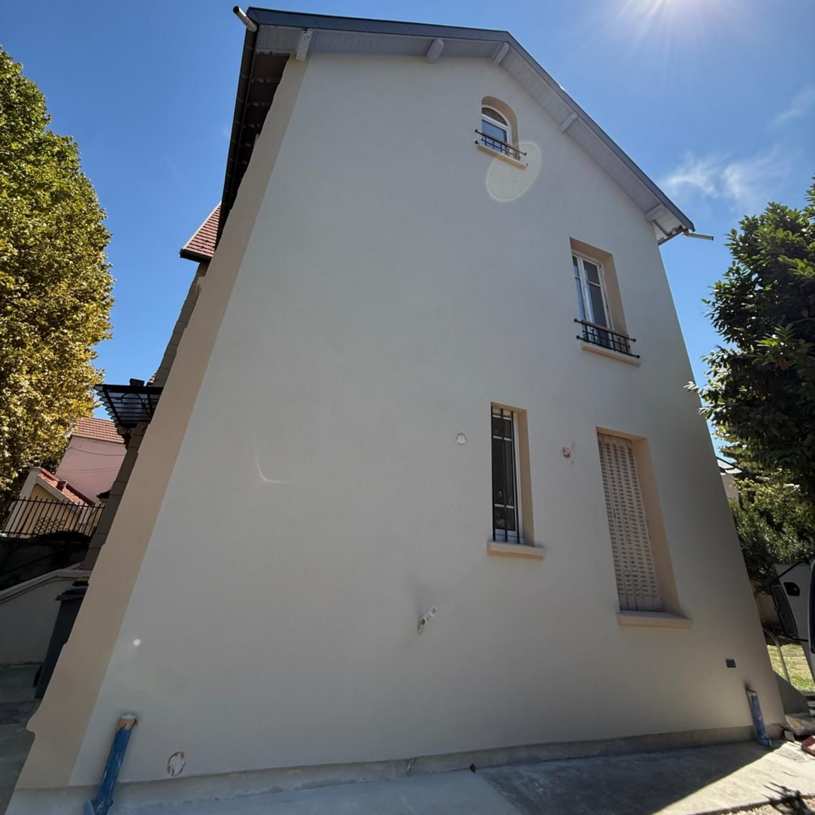 Maison en stuc blanc au toit pentu, vue d'en bas par une journée ensoleillée