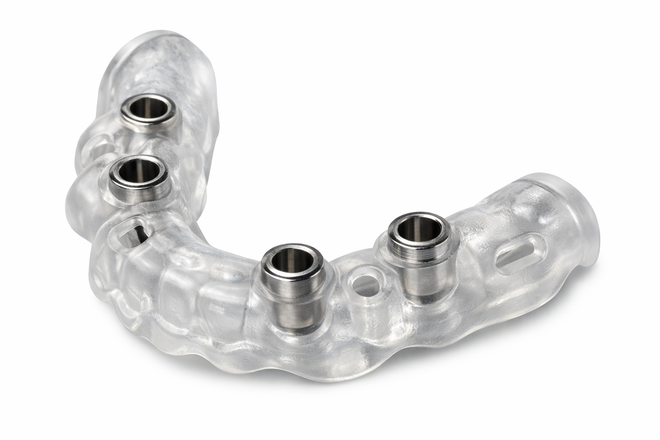 Alineador dental transparente con cuatro orificios para tornillos metálicos sobre un fondo blanco.