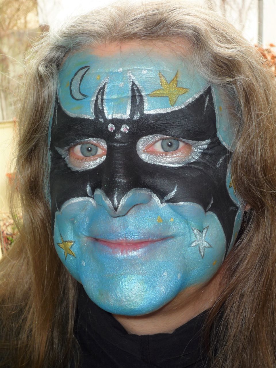 Eine Frau lässt ihr Gesicht so bemalen, dass sie wie Batman aussieht.