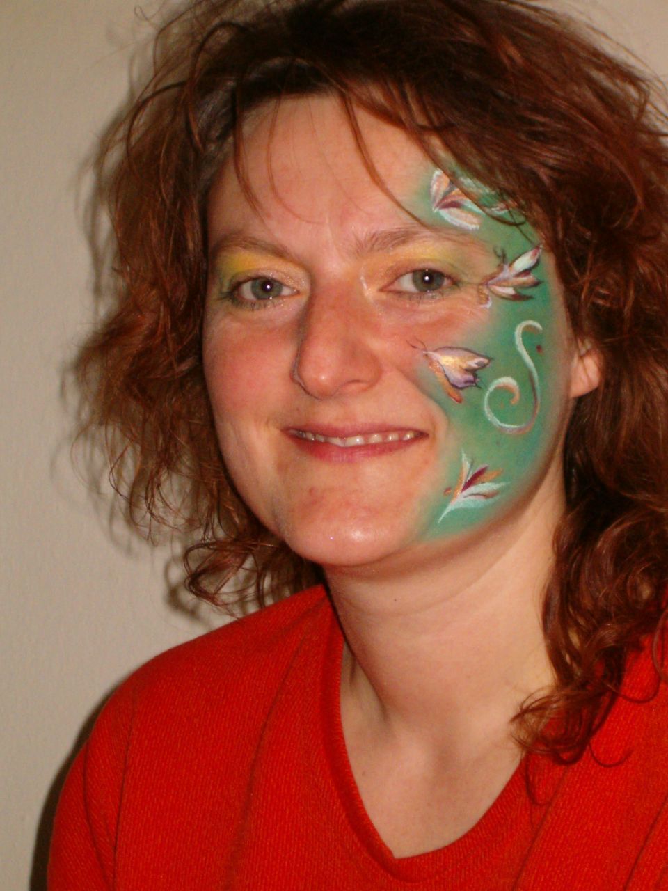 Eine Frau mit bemaltem Gesicht trägt ein rotes Hemd