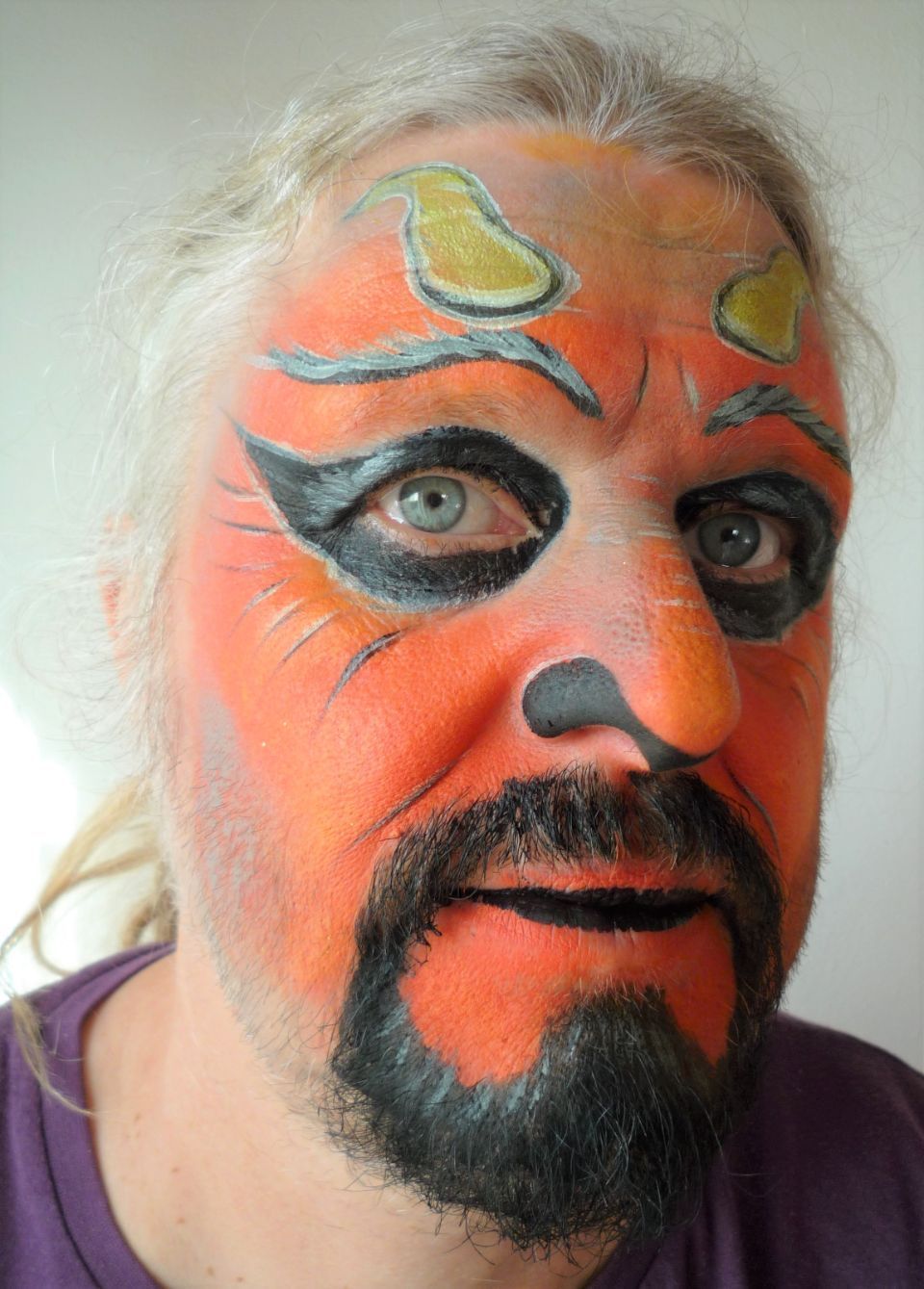 Ein Mann mit Bart hat sein Gesicht wie ein Teufel bemalt
