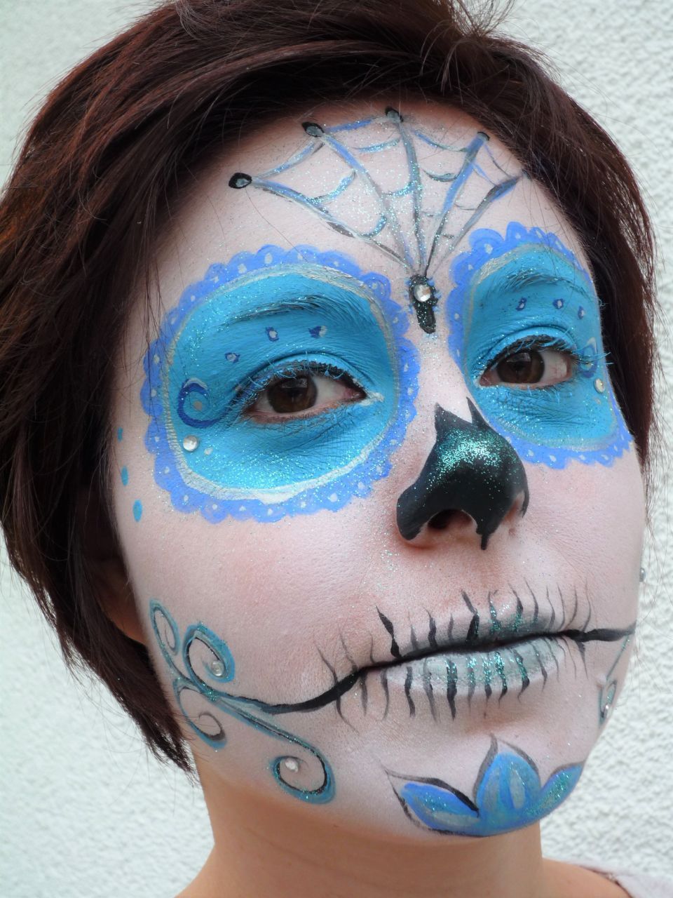 Eine Frau hat ihr Gesicht wie einen Zuckerschädel bemalt