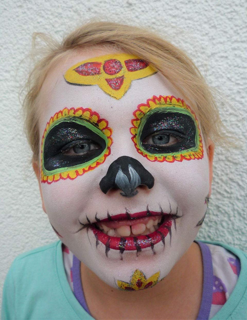 Ein junges Mädchen hat ihr Gesicht wie einen Zuckerschädel bemalt