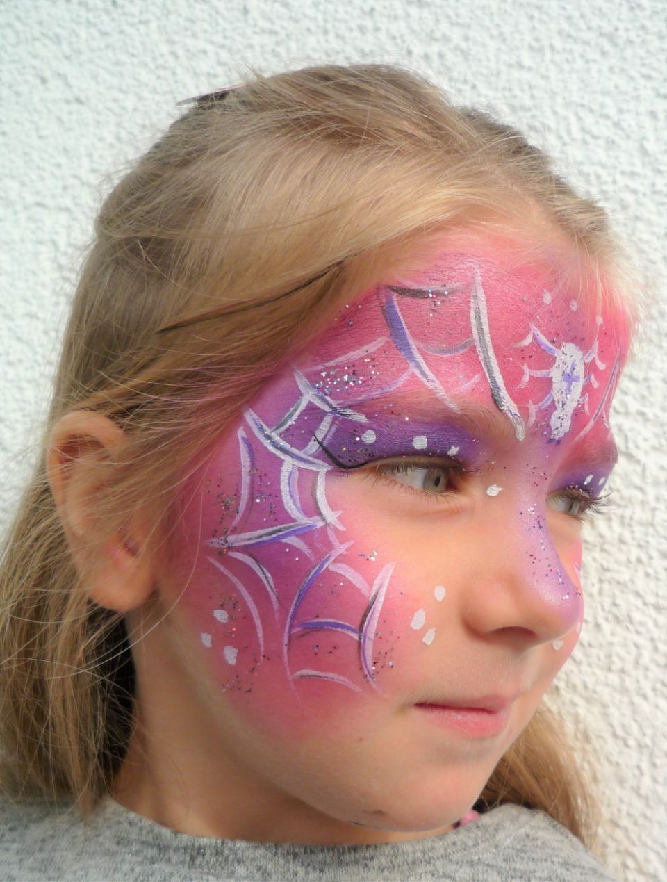 Ein kleines Mädchen mit einem auf das Gesicht gemalten Spinnennetz.