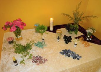 Ein Tisch mit Blumen, Kerzen, Kristallen und Flaschen darauf.