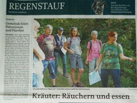 Eine Gruppe von Menschen steht vor einer Zeitung mit der Aufschrift „Regenstauf“