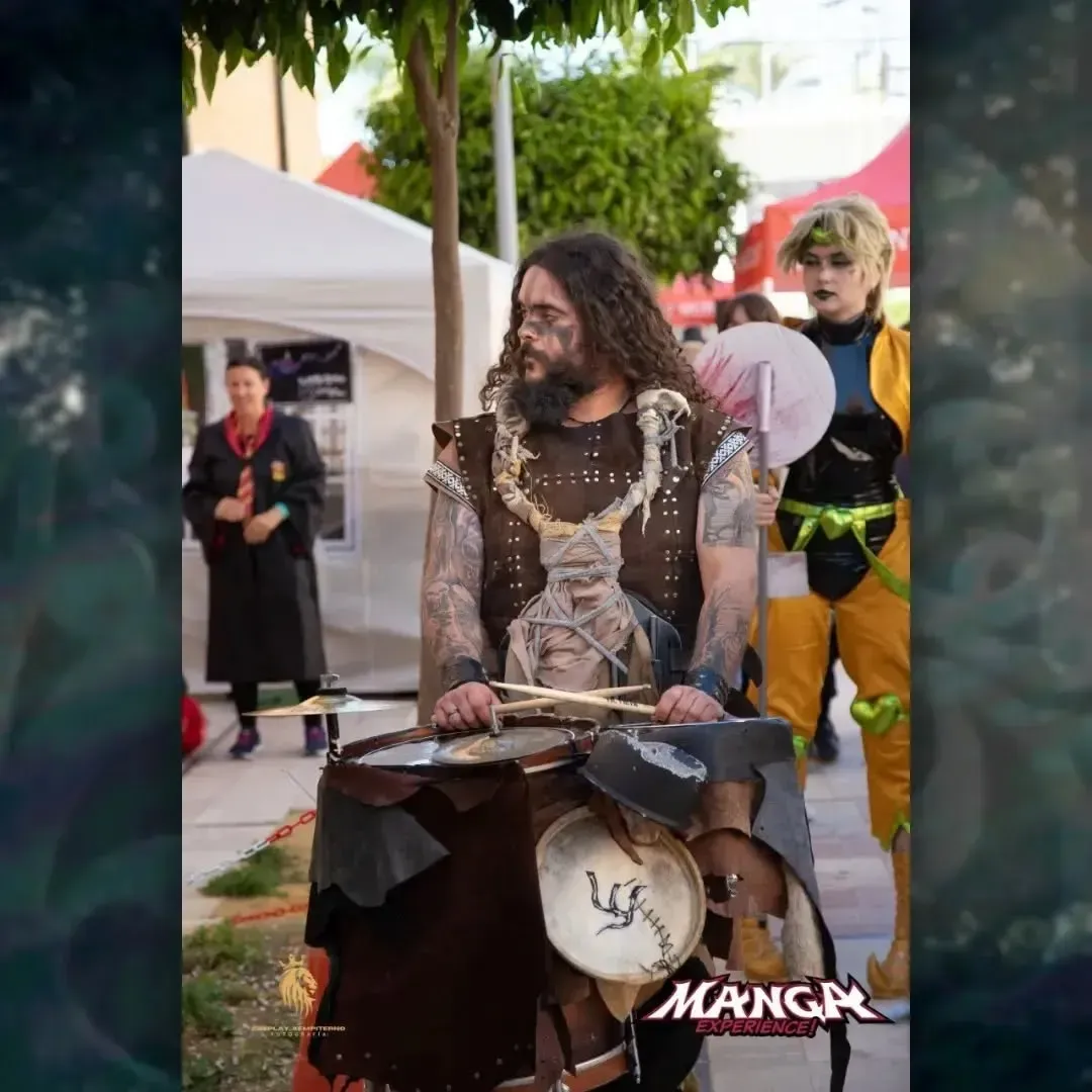 Cosplayer con tambor, persona con traje amarillo, entorno al aire libre.