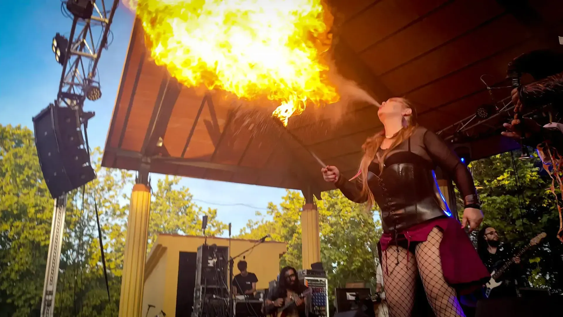 Mujer disfrazada escupe fuego en el escenario, escenario de una actuación.