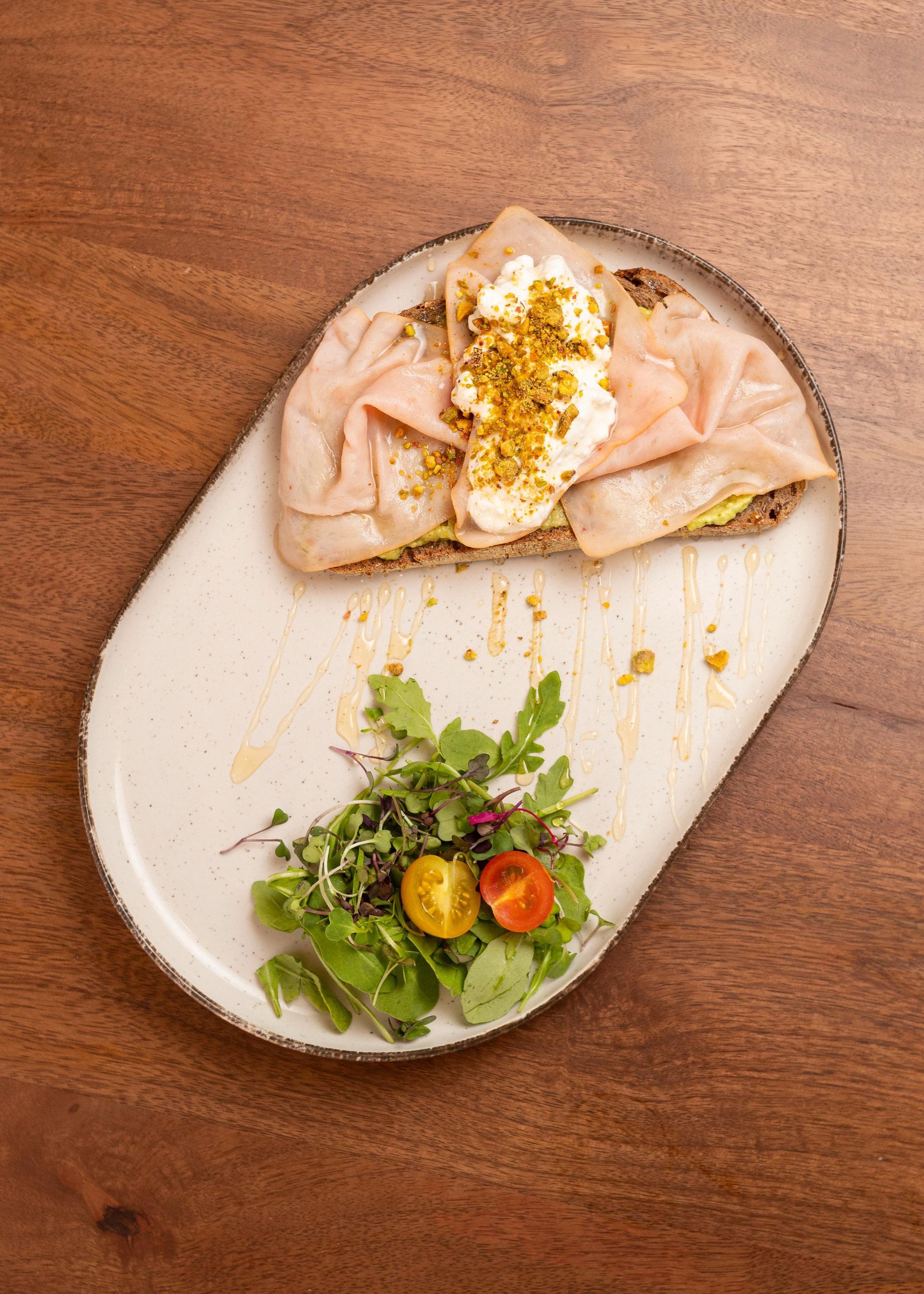 Salmón emplatado con verduras y hortalizas en un plato blanco sobre una mesa de madera.