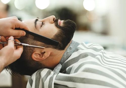 Un hombre se está recortando la barba en una barbería.