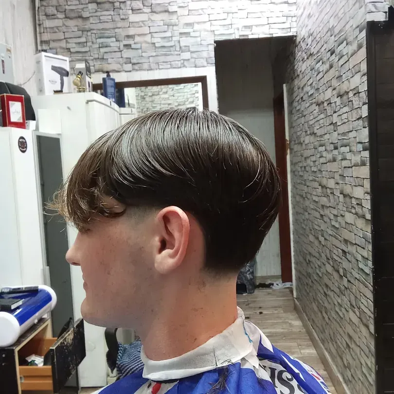 Un joven se está cortando el pelo en una peluquería.