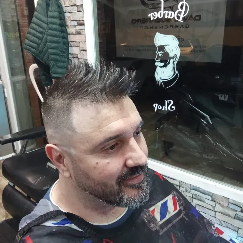 Un hombre con barba se está cortando el pelo en una barbería.