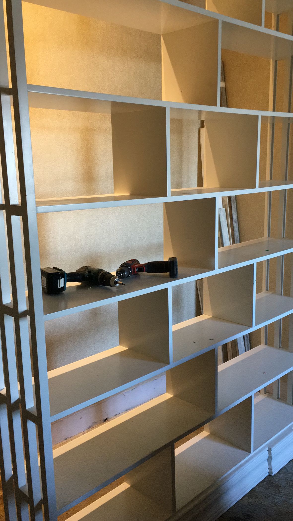 Estantería blanca con múltiples compartimentos, herramientas en un estante.