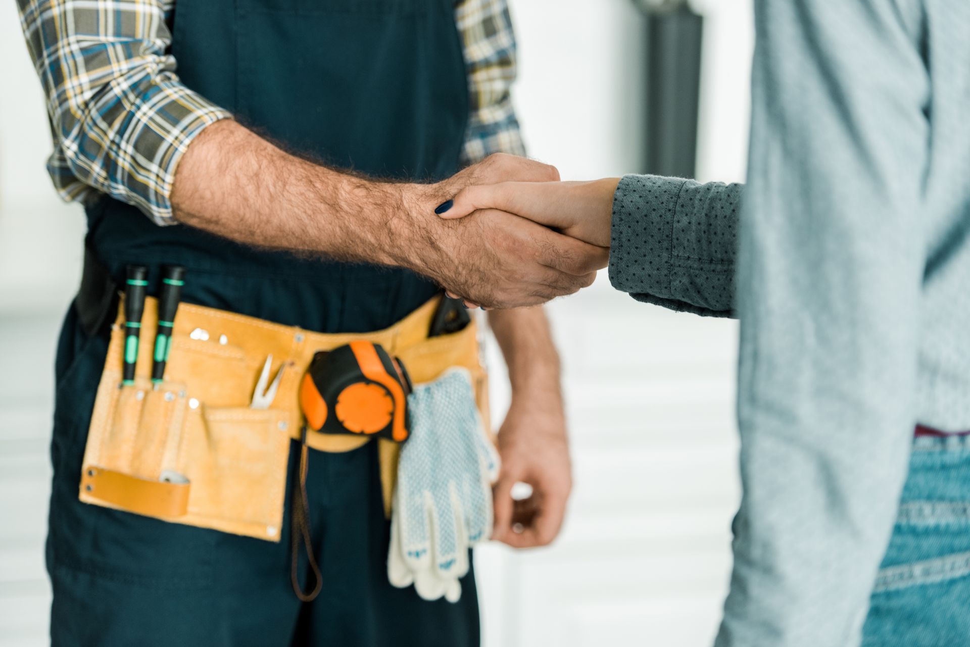 Silhouette d'un artisan avec une ceinture d'outils qui serre la main d'une femme