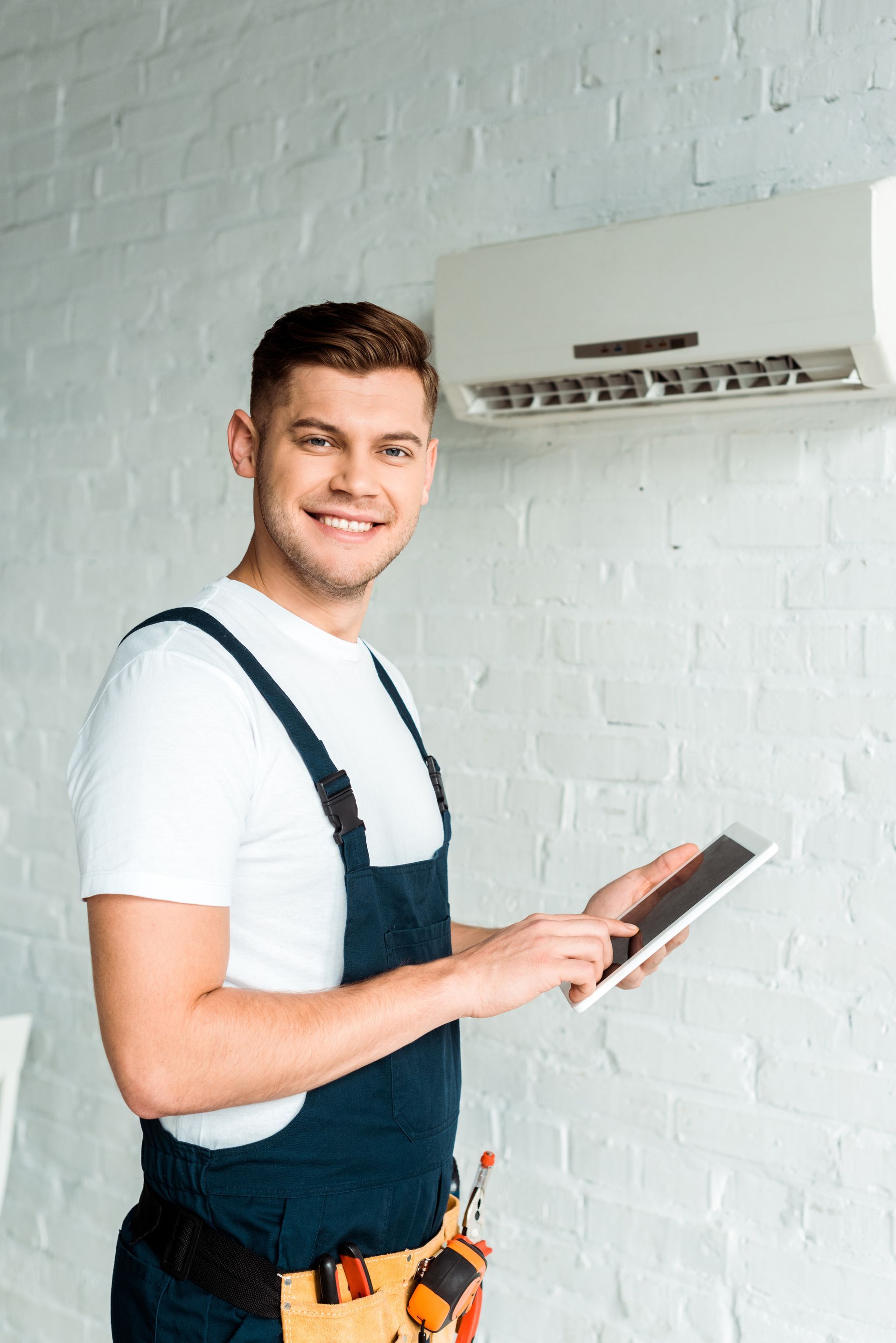 Technicien naviguant sur sa tablette après l'installation d'une climatisation murale