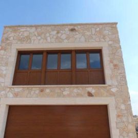 Un edificio de piedra con puerta de garaje y ventanas de madera.