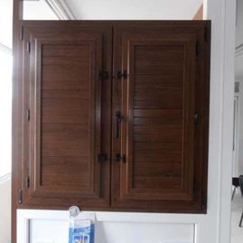 Un primer plano de un armario de madera con persianas en una habitación.