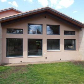 Una casa grande con muchas ventanas y un césped delante de ella.
