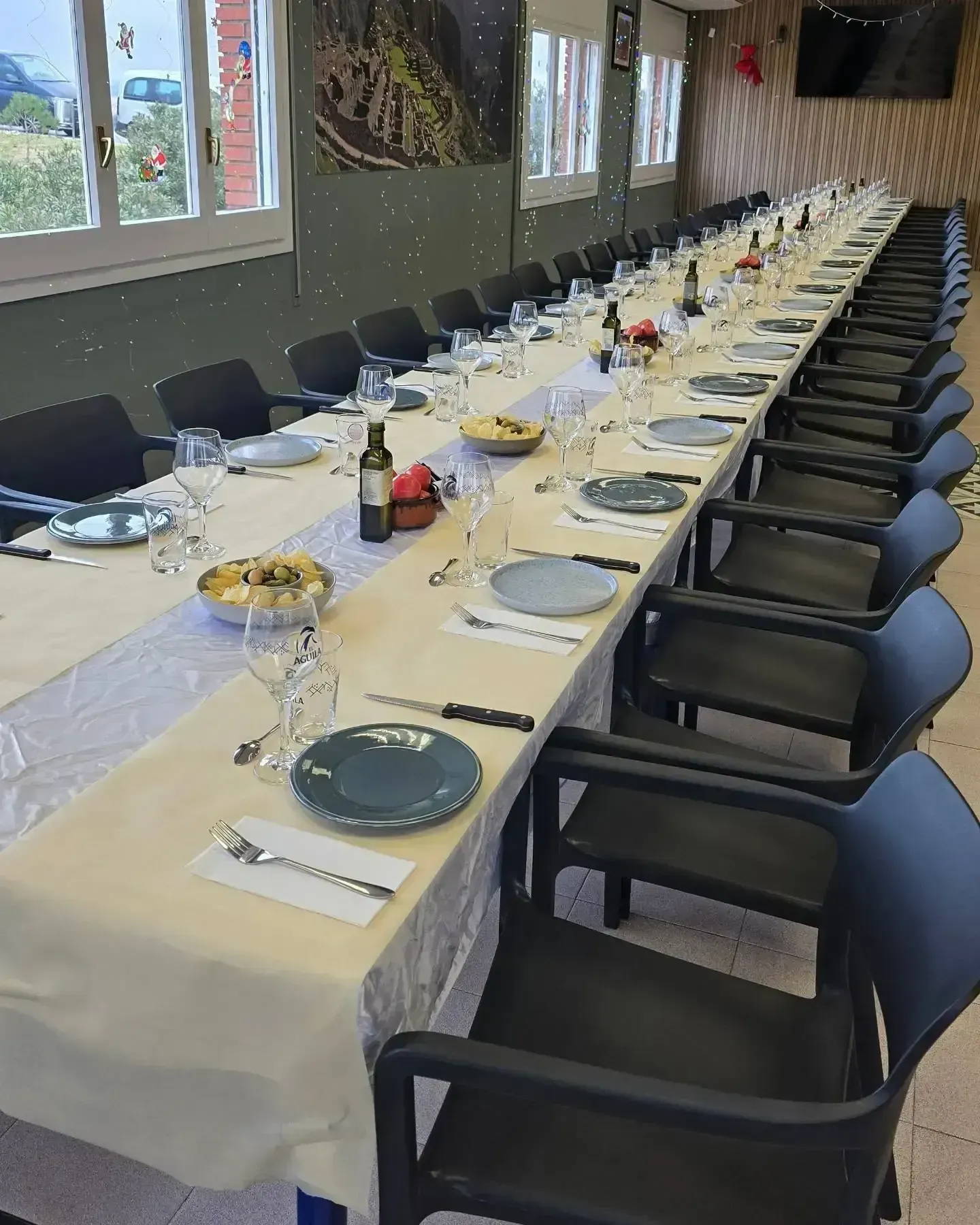 Mesa de comedor larga para comer, con platos, vasos y sillas.