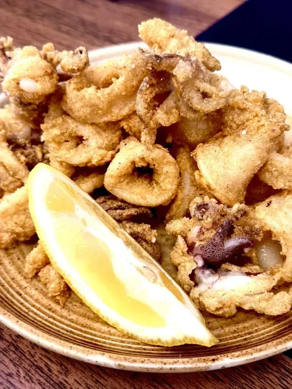 Calamares fritos con una rodaja de limón en un plato.