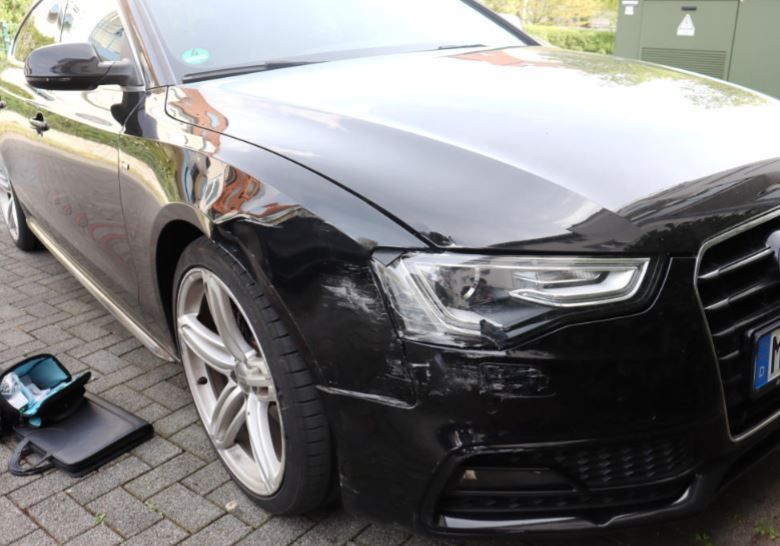 Bild einer beschädigten PKW-Front, schwarz
