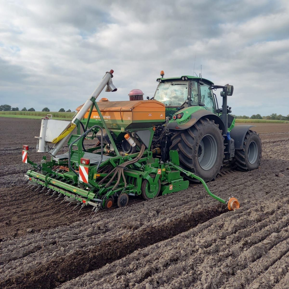 Ein grüner Traktor pflügt ein Feld mit einer daran befestigten Maschine