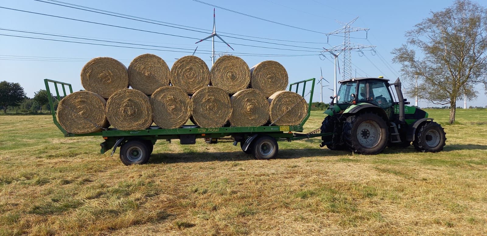 Ein Traktor zieht einen Anhänger voller Heuballen.