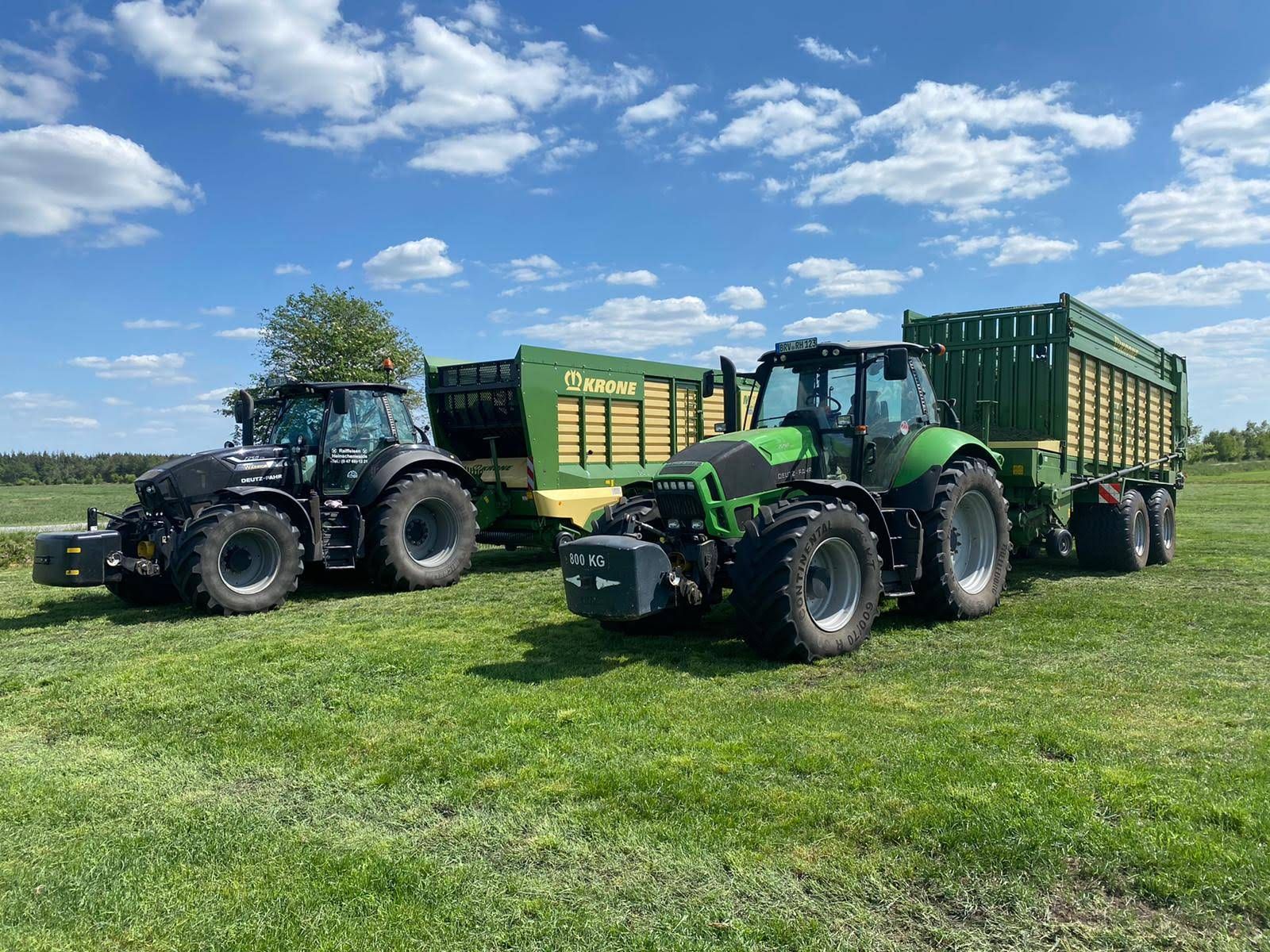 Zwei Traktoren sind nebeneinander auf einer Wiese geparkt.