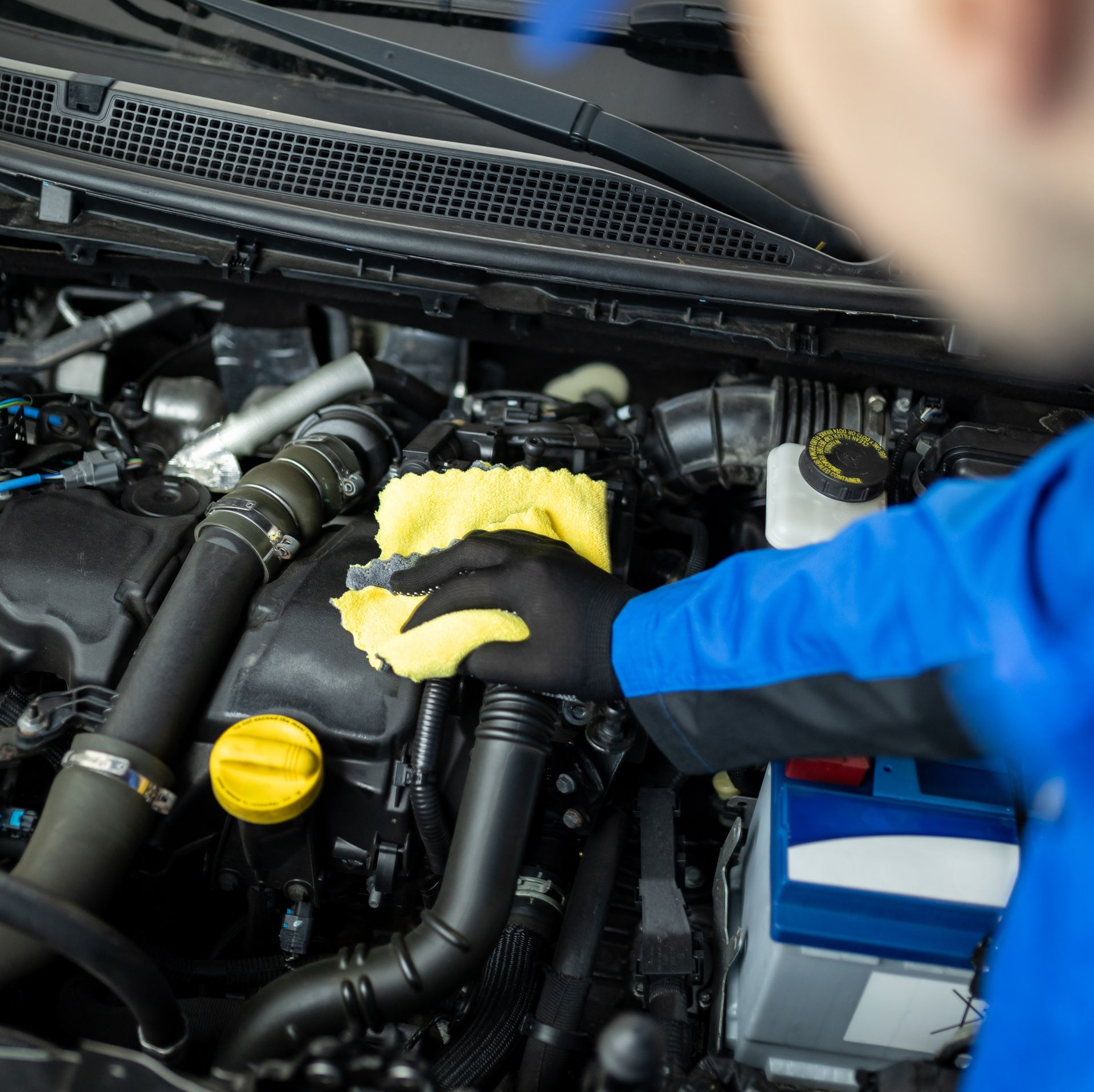 Un monsieur passe le chiffon dans le moteur d'une voiture