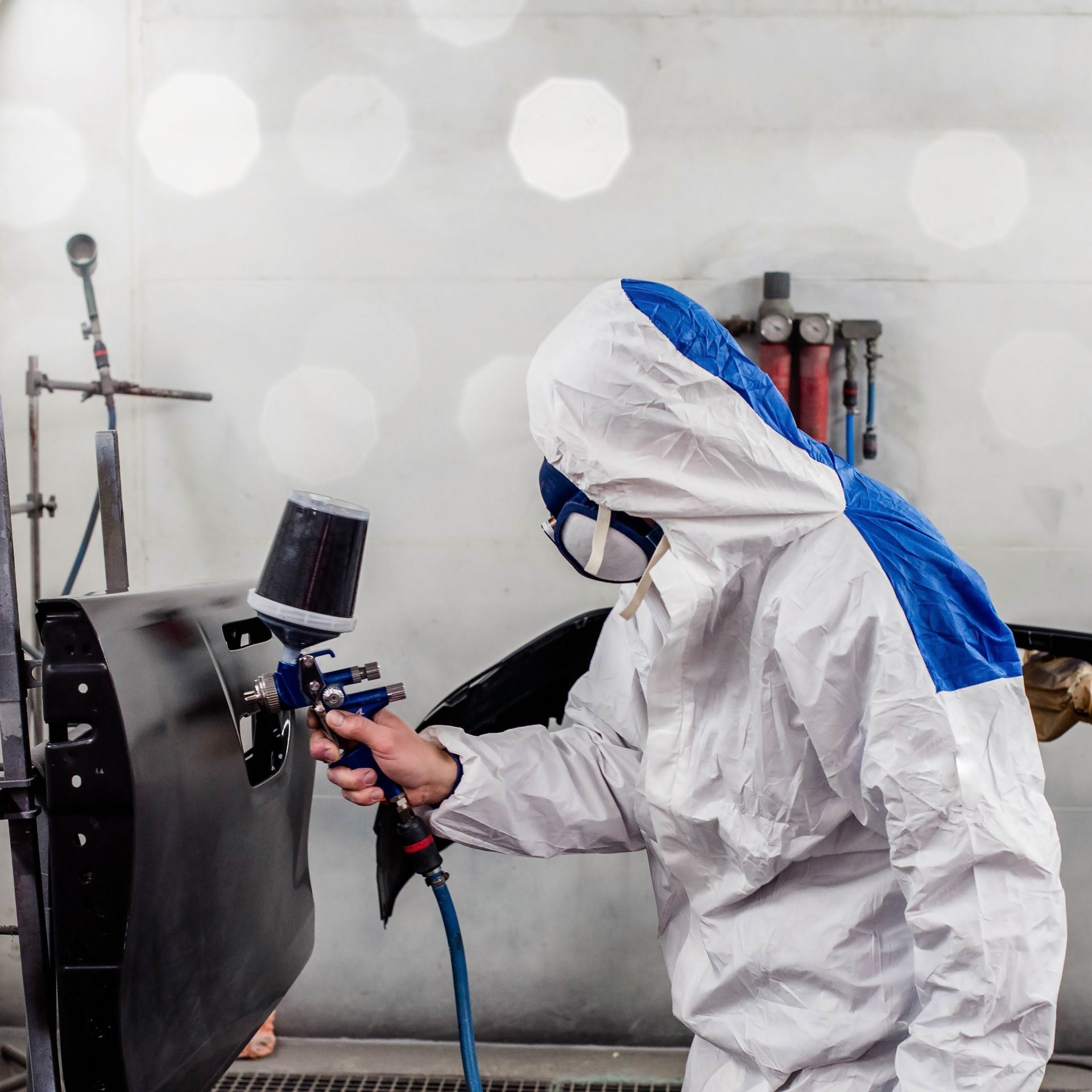 Un monsieur portant une combinaison ponce une partie de la carrosserie