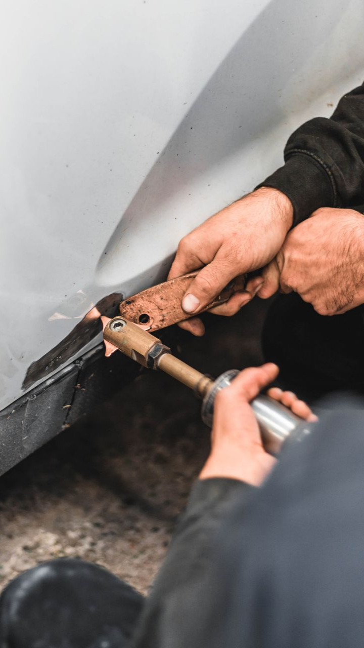 Des personnes avec des outils travaillent sur la carrosserie d'une voiture