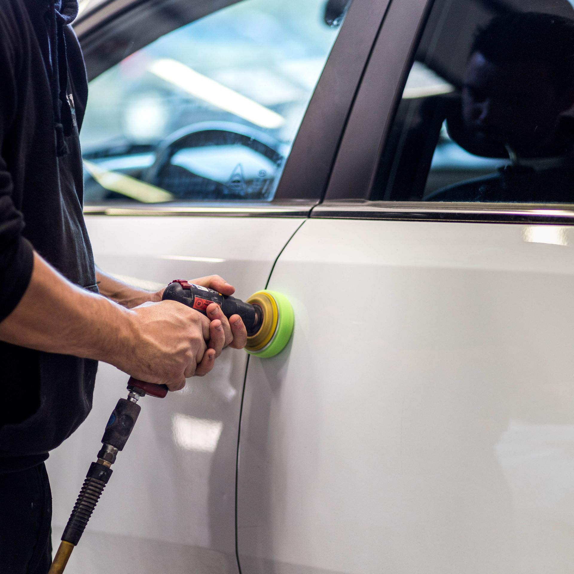 Une personne tient un outil sur la carrosserie d'une voiture