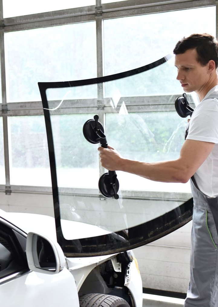 Un homme porte le pare-brise avec des ventouses d'une voiture