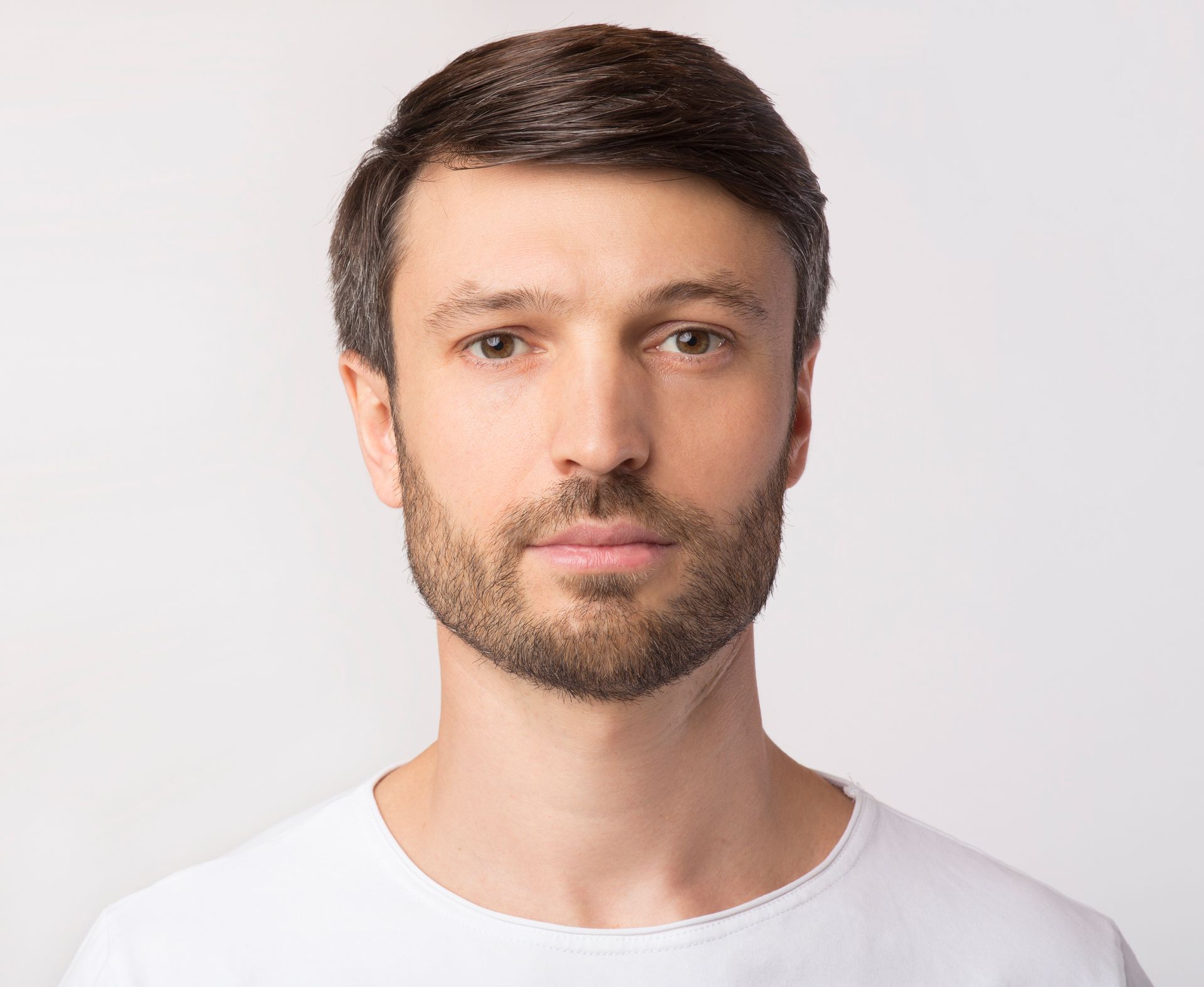 Portrait d'un homme d'âge moyen regardant l'objectif sur fond blanc de studio.