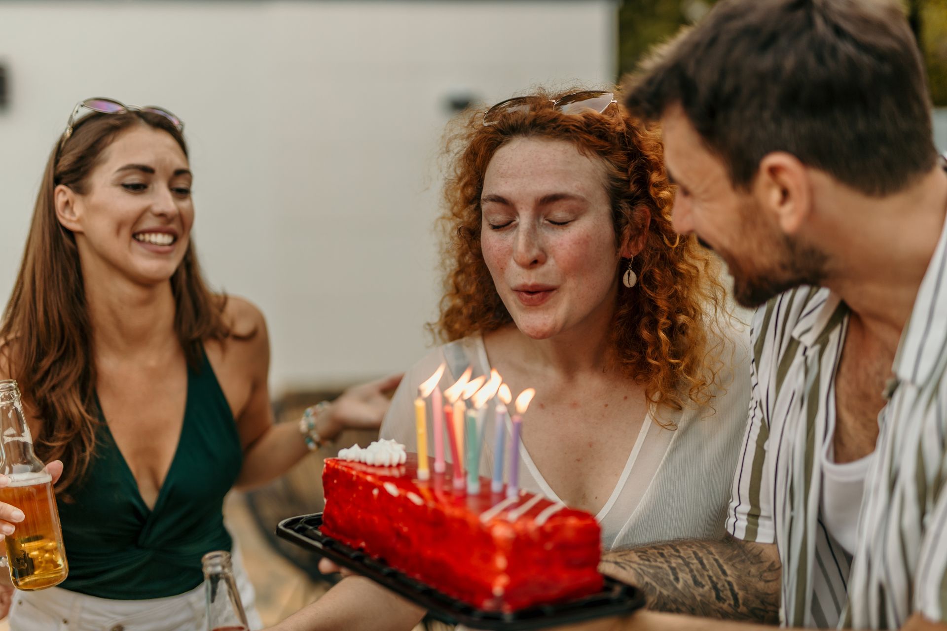 Une jeune femme soufflant ses bougies d'anniversaire entourée de ses amis.