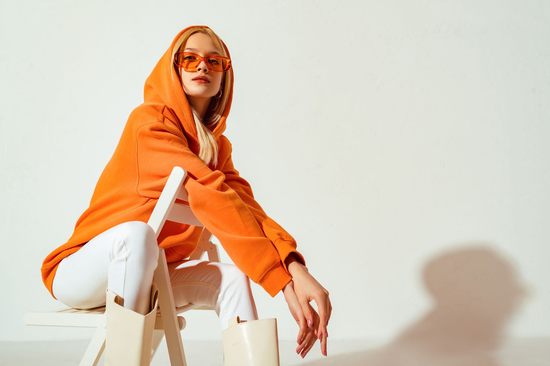 Jeune fille blonde confiante, portant un sweat à capuche orange tendance et des lunettes de soleil colorées