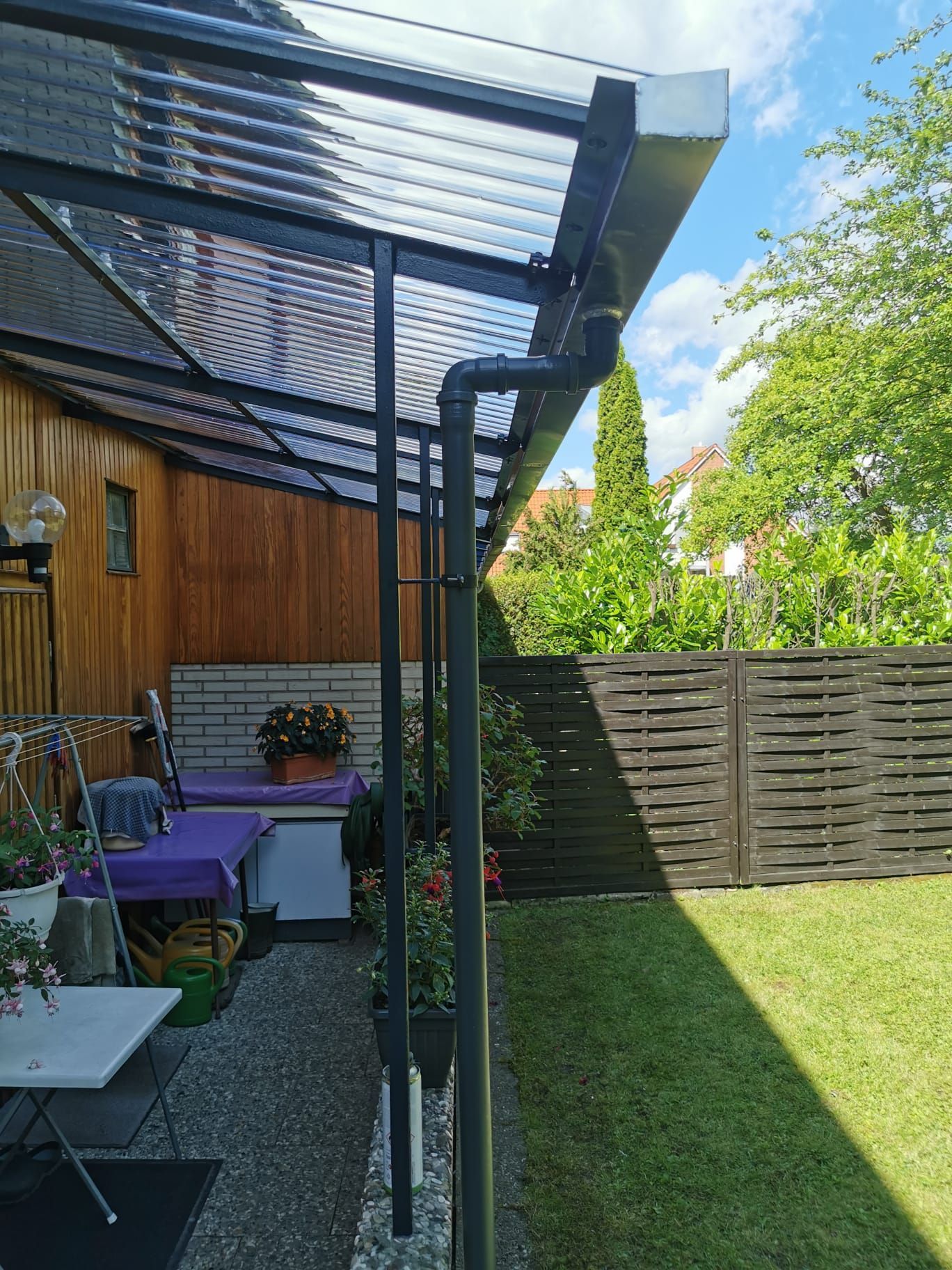 Im Hinterhof gibt es einen Tisch und Stühle unter einem Vordach.