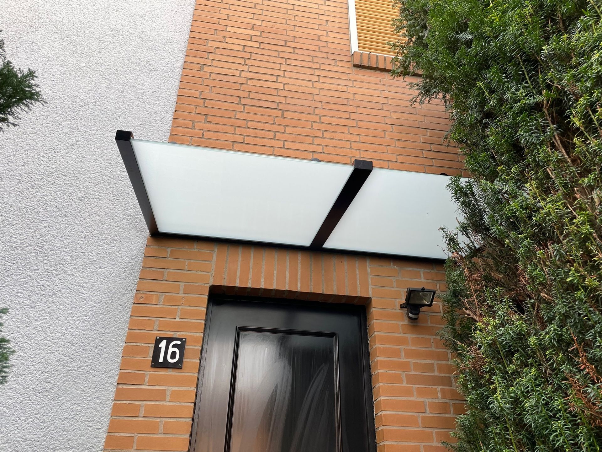 Die Eingangstür mit Vordach eines Backsteingebäudes 