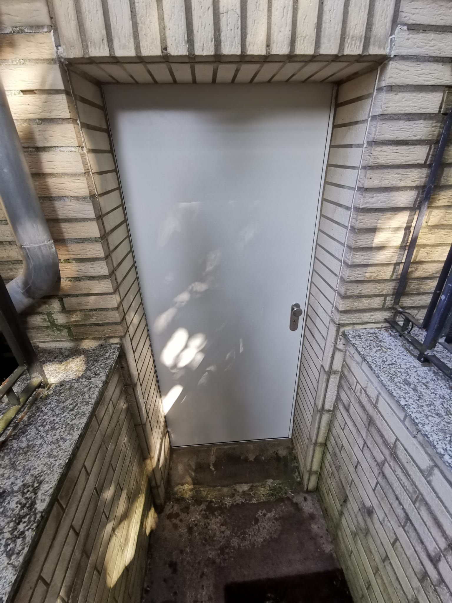 Zwischen zwei Backsteinwänden befindet sich eine weiße Tür.