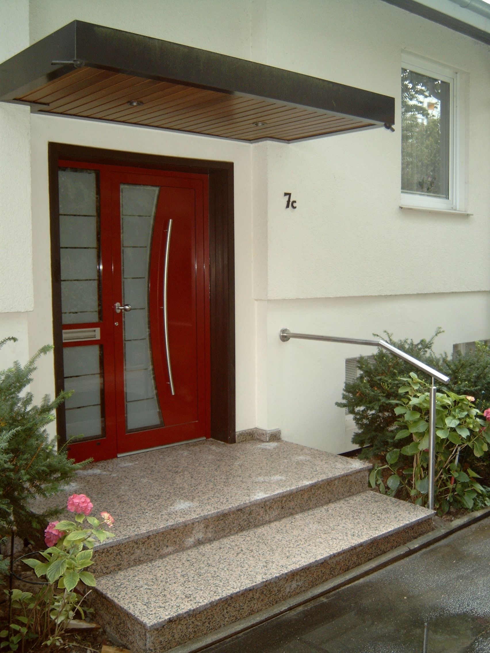 Ein weißes Haus mit einer roten Tür und Treppe