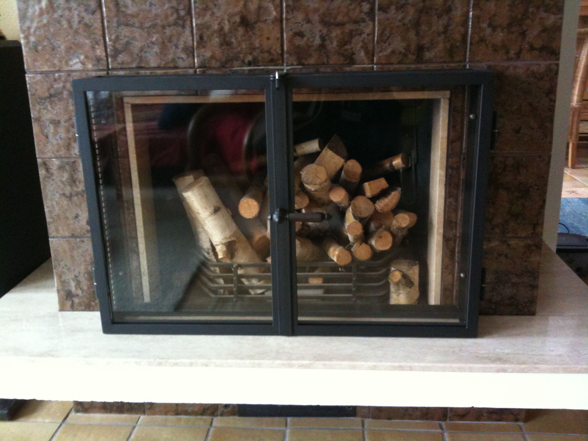 Ein Kamin mit einer Glastür, gefüllt mit Holzscheiten