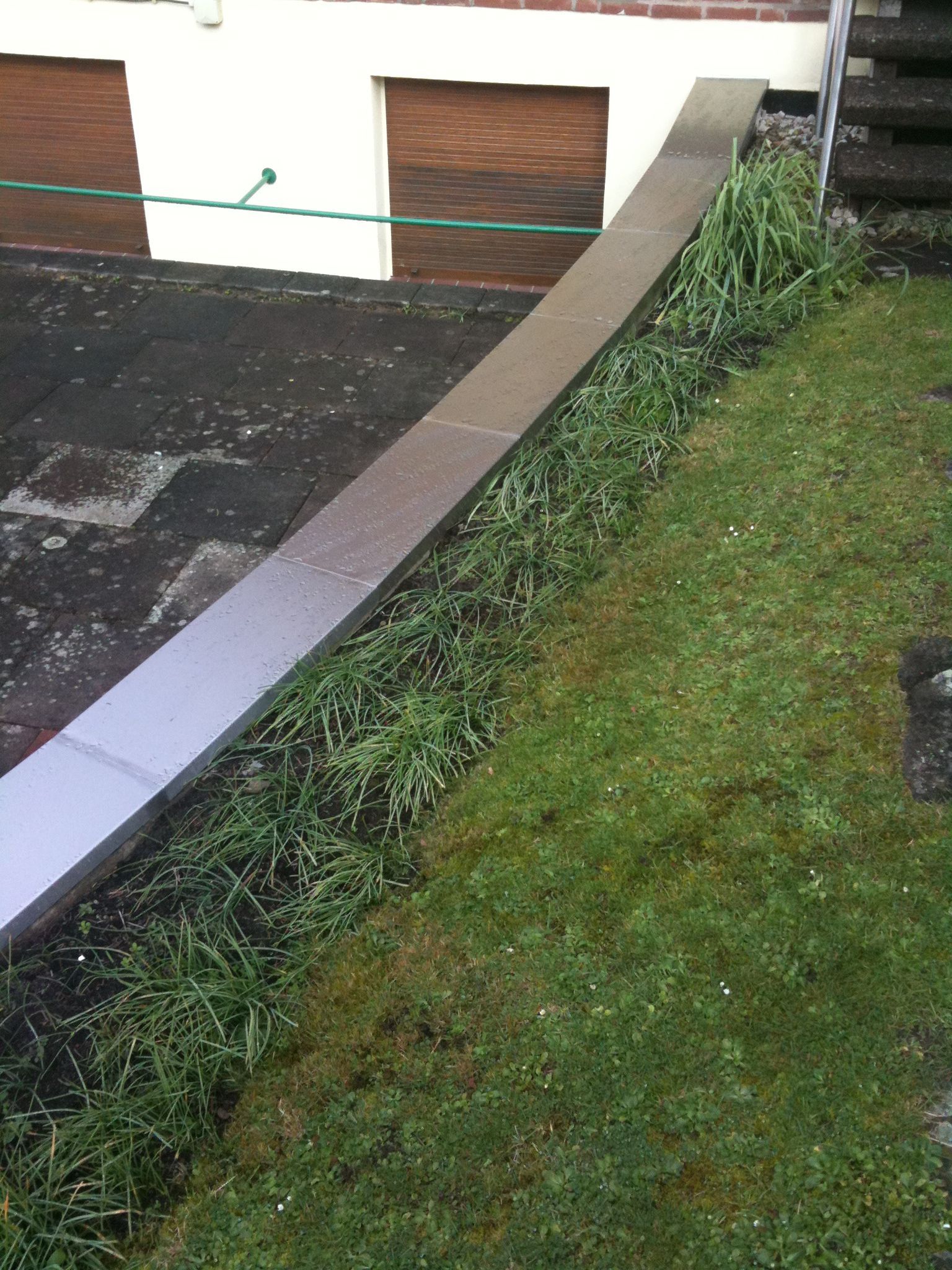 Vor einem Haus ist ein Edelstahlzaun von grünem Gras umgeben.