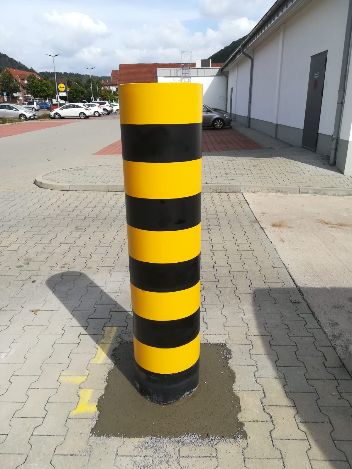 Ein gelb und schwarz gestreifter Pfosten auf einem Parkplatz