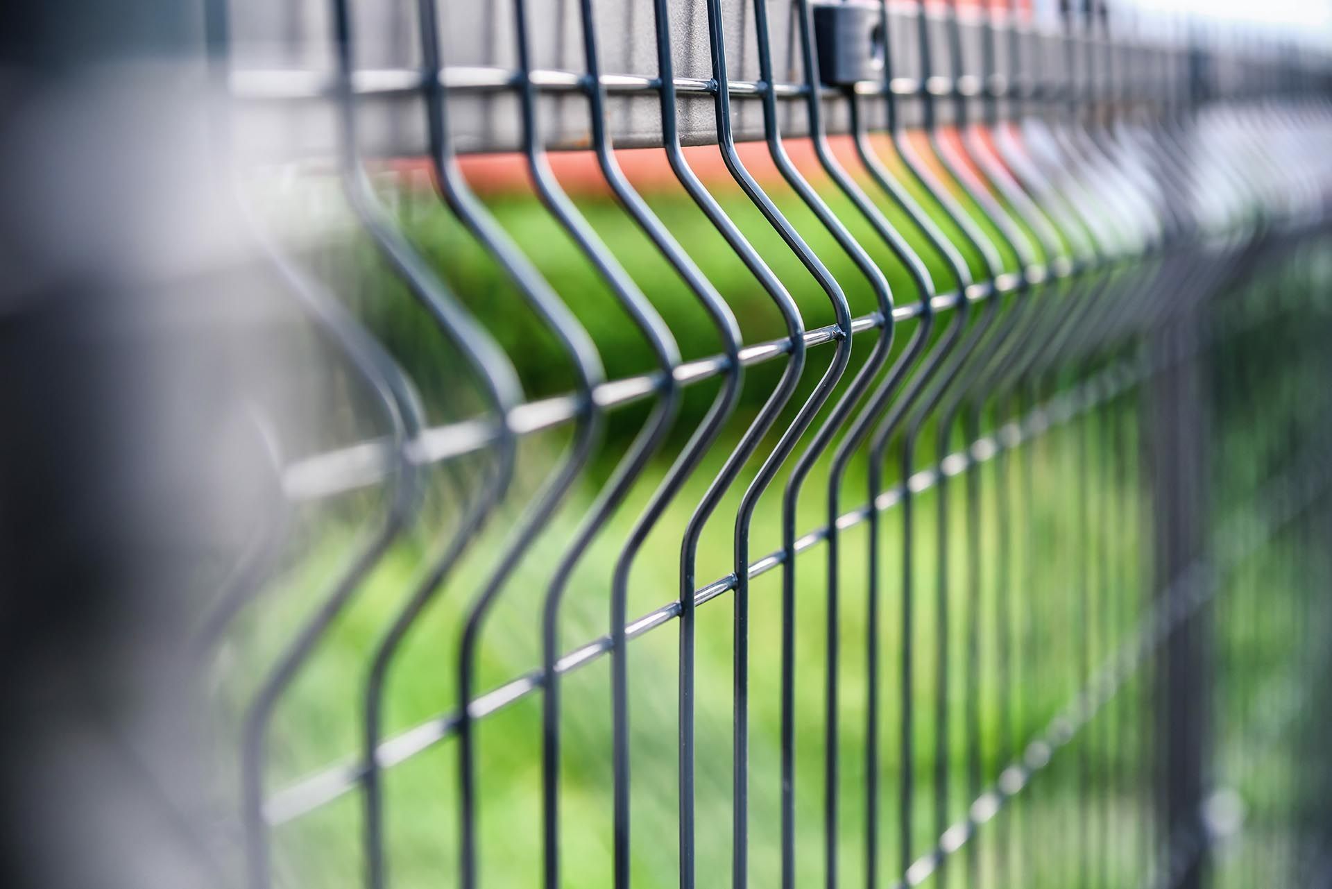 Eine Nahaufnahme eines Metallzauns vor grünem Hintergrund.